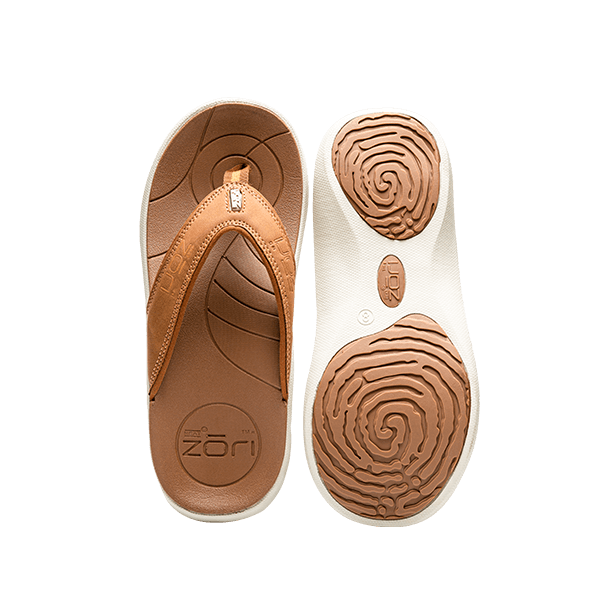 Neat Zori Sahara Slimline Orthotic Sandals arranged side by side, with one sandal flipped onto its back to reveal its grippy white underside featuring two brown pads at the front and heel.