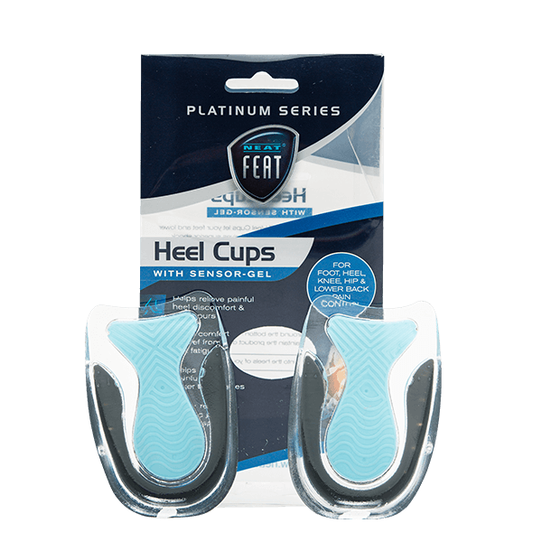 Both Neat Feat Heel Cups standing upright in front of the packaging. The cups are mostly clear, featuring a blue heel pad and a black trim around the base of the heel for added support.